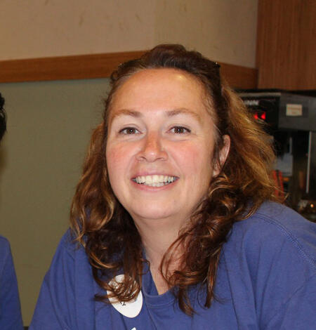 headshot of a woman smiling at the camera and wearing a violet t-shirt